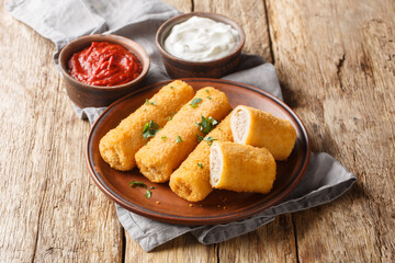 Krokiety is a traditional Polish side dish consisting of crepes filled with meat, then breaded and fried closeup on the plate on the wooden table. Horizontal