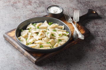 Traditional Polish Christmas Eve mushroom dumplings uszka served with sour cream closeup on the plate on the table. Horizontal