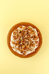 sponge cake with cream and nuts on a yellow background