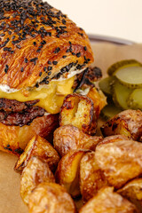 burger with beef patty, cheese sauce on a plate with potatoes