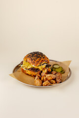 burger with beef patty, cheese sauce on a plate with potatoes