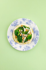 hummus on a plate with broccoli, nuts and cheese