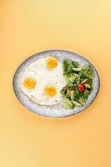 fried eggs and fresh vegetables on a plate . breakfast