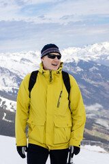 Fototapeta na wymiar Athlete in yellow jacket and sunglasses, alpine snow-capped peaks