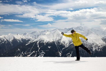 Skier simulates ski step. Snow-capped Alps. Mountain, blue sky, clouds