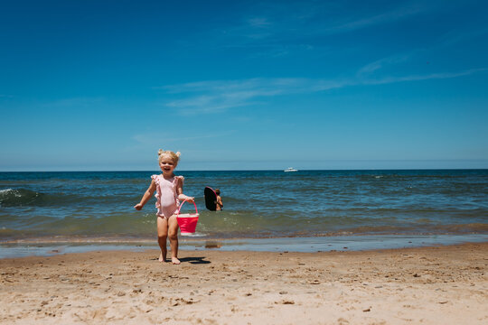 Young child with sand bucket on beach of Lake Michigan