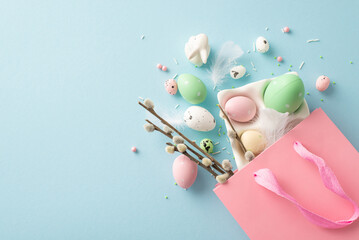 Spring pastry delights promo: Top view shot of a pink bag holding festive treats - eggs, adorable bunny, pussy willow, and sugar sprinkles. Pastel blue backdrop with space for your message