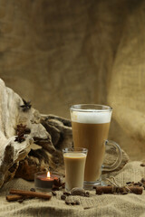 Glass coffee with glass of irish cream liqueur and spices. Cloth background with copy space