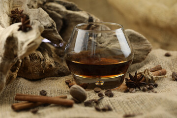 Glass of cognac with spice. Cloth background with copy space