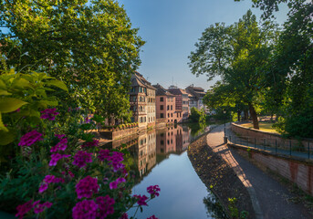 Strasbourg, France. Ancient houses of the Petite France district on the embankment of the Ille River with flowers in the foreground in the early morning.