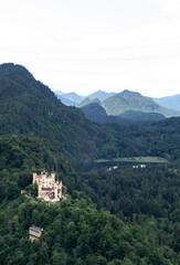 Fototapeta na wymiar View of Hohenschwangau castle located at the top of a hill, surrounding of a forest, a lake and mountains in Germany.