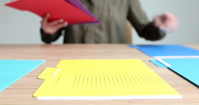 Secretary laying out multicolored folders with documents on table in office closeup 4k movie. Seminars and business meeting concept