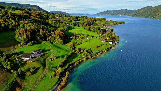 Aerial view of a vibrant lakeside community with lush greenery and clear blue waters at attersee lake