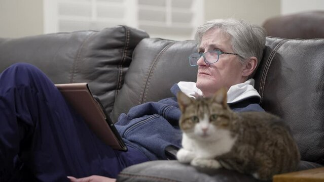 Single senior widow woman watching television with her cat
