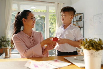 Smiling School boy, giving, apple to his favorite teacher