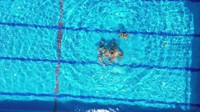 Aerial view of eight teenage girls learn synchronized swimming in the pool. Girls learn competitive swimming in the pool. Team water sports.