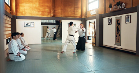 Aikido, sensei and Japanese students with training, fitness and action in class for defence or...