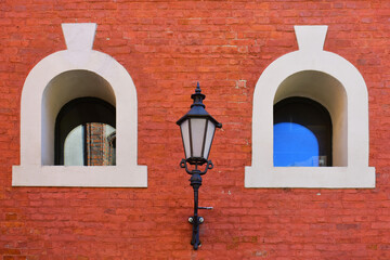 Facade of the historic building with two small semicircular windows, white frames, street lantern...