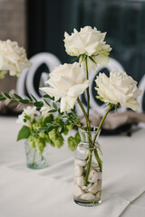Beautiful flowers on a table on wedding day. Elegant white decor for a event dinner. The table are decorated with white flowers in glass vase. Details closeup.