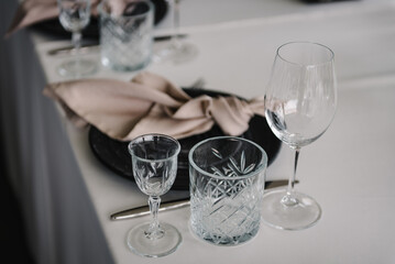 Black plate and glass, stack, wine glass, luxury rich decor. Serving, setting table. Wedding set up, dinner table reception on terrace. Birthday, baptism, event. Closeup details of interior. Side view
