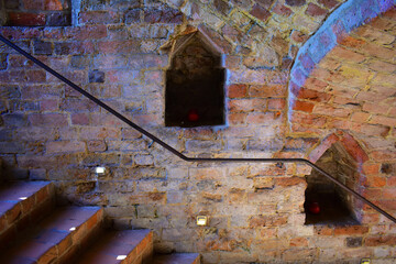 Ancient dark red brick basement with an arched windows and staircase. Ancient historical castle. Poland, Torun, August 2023.