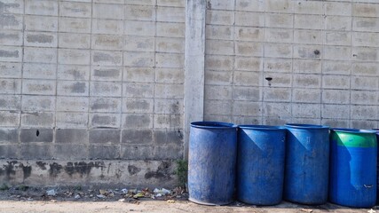 Several blue trash can sits along the wall
