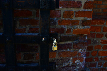 Antique metal lock on a massive wooden medieval frame and a dark brick wall. Security.