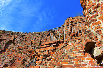 Old brick dilapidated wall. Ruins of the fortress. Ancient building against a blue sky background. Poland, Torun, August 2023. 