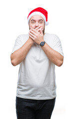 Young caucasian hipster man wearing christmas hat over isolated background shocked covering mouth with hands for mistake. Secret concept.