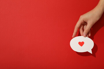 Paper message icon with heart in hand on red background, space for text