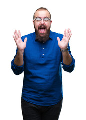 Fototapeta premium Young caucasian hipster man wearing glasses over isolated background celebrating crazy and amazed for success with arms raised and open eyes screaming excited. Winner concept