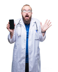 Young doctor man showing smartphone screen over isolated background very happy and excited, winner expression celebrating victory screaming with big smile and raised hands