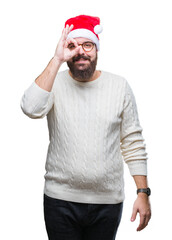 Young caucasian man wearing christmas hat and glasses over isolated background doing ok gesture with hand smiling, eye looking through fingers with happy face.