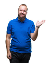 Young caucasian hipster man wearing blue shirt over isolated background smiling cheerful presenting and pointing with palm of hand looking at the camera.