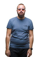 Young caucasian hipster man wearing sunglasses over isolated background with serious expression on face. Simple and natural looking at the camera.