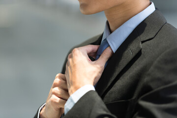 Close up detail of businessman adjusting his tie.