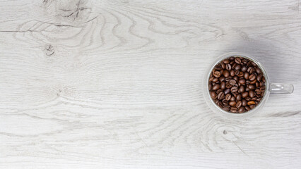Banner with glass cup of coffee beans on white wooden background top view