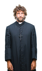 Handsome hispanic catholic priest man over isolated background with serious expression on face. Simple and natural looking at the camera.