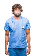 Fototapeta premium Handsome hispanic surgeon doctor man over isolated background puffing cheeks with funny face. Mouth inflated with air, crazy expression.