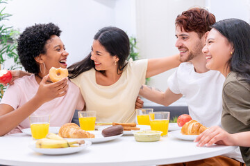 Friends from Afro American, Hispanic, and Asian backgrounds enjoy a laughter-filled breakfast