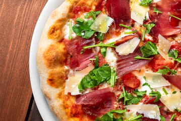 Deliziosa pizza con speck, scaglie di parmigiano, pomodoro e rucola, cibo italiano 