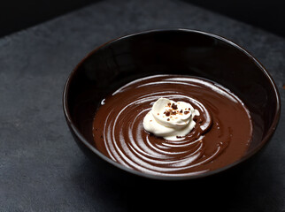 Bowl of hazelnut cream, chocolate paste swirl on black background