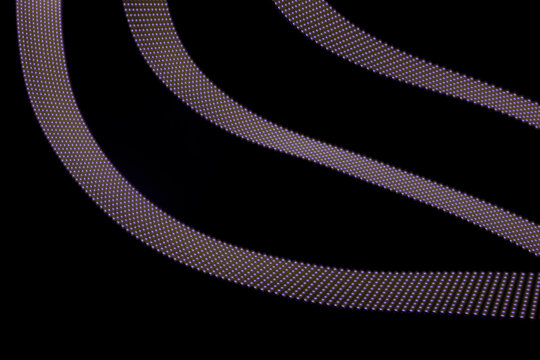 Violet neon curved wave of light with dotted stripes on black background, pattern. Abstract background with dynamic line in motion, light painting in modern style.