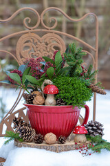 Silvester-Dekoration mit Holz-Fliegenpilz, Skimmia und Strauchveronika im Porzellantopf im Wintergarten