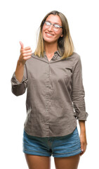 Young beautiful woman over isolated background doing happy thumbs up gesture with hand. Approving expression looking at the camera with showing success.