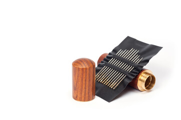 Metal sewing needles for hand sewing on a faux leather base and a container for storing them.