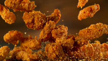 Freeze motion shot of falling tasty fried chicken wings or strips