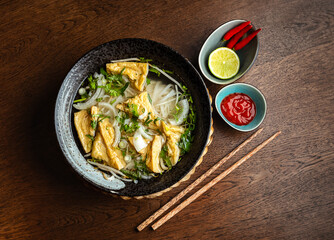 Asian vegetarian noodle soup in a ceramic plate