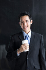 Chinese Business man leaning on a black wall