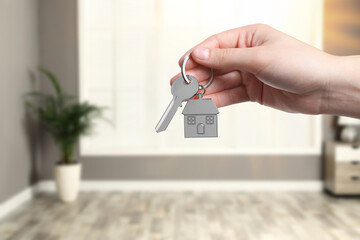 Woman holding house key in room, closeup